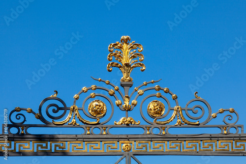 Baroque ornament on a metal gate against a blue sky