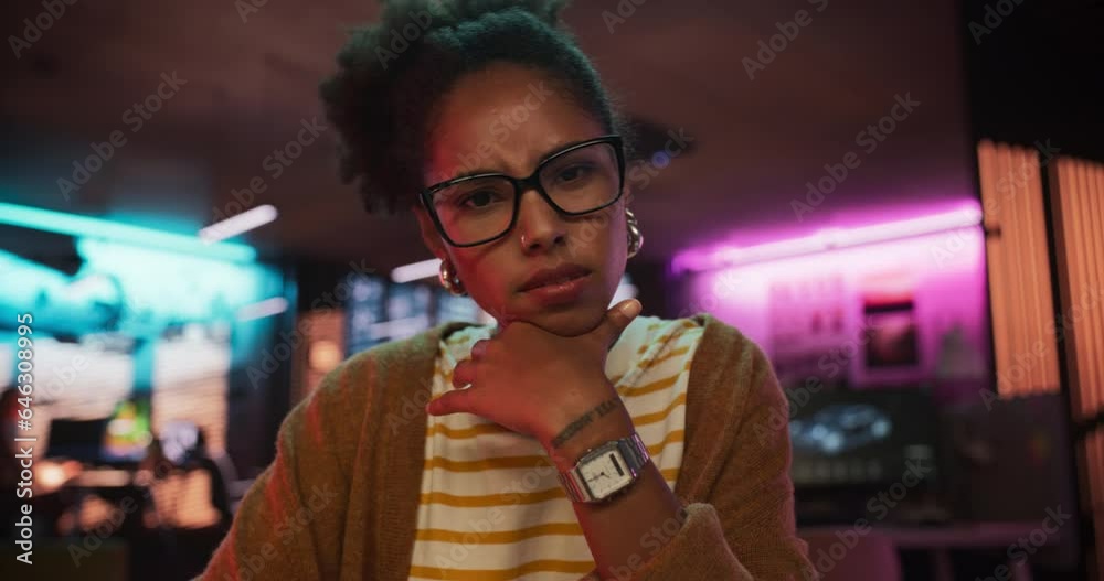 Zoom in: Stylish Young Black Woman Looking at Camera With Confusion While Working on Desktop Computer in Creative Office. Female Developer Trying to Fix a Bug, Unsure of the Source of the Issue
