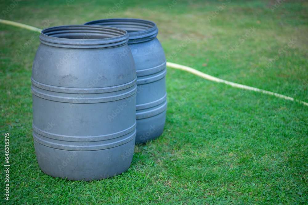 Plastic water barrels in the garden.Two large barrels are on the ground.Stock up on water. Plastic water barrels in the garden.Two large barrels are on the ground.Stock up on water.