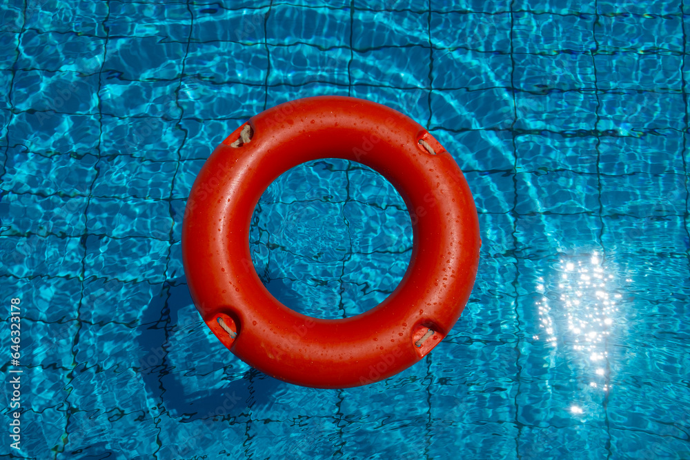 Konzept Sicherheit im Schwimmbad mit einem orangenfarbenen Rettungsring im Pool - obrazy, fototapety, plakaty 