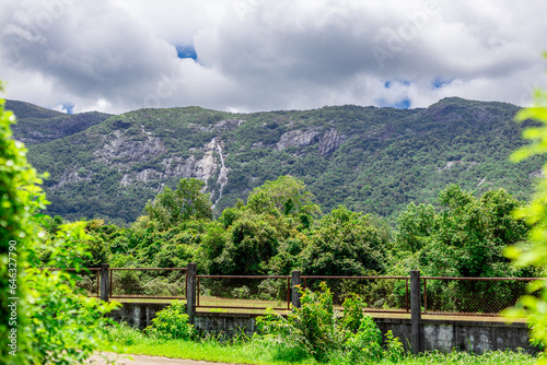 background of a religious tourist attraction in the Ranong area of Thailand Wat Baan Ngao)has beautiful sculptures and a statue of Luang Pho Dibuk.Can see Ngao Waterfall surrounding grassy moutains photo