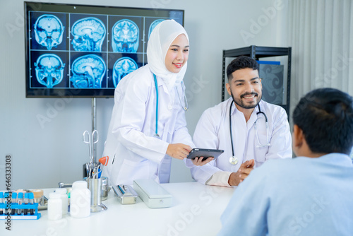 Muslim male and female doctors in medical uniforms was sitting at the patient's examination table and was examining and talking about the patient with a smiling and worried face in hospital.
