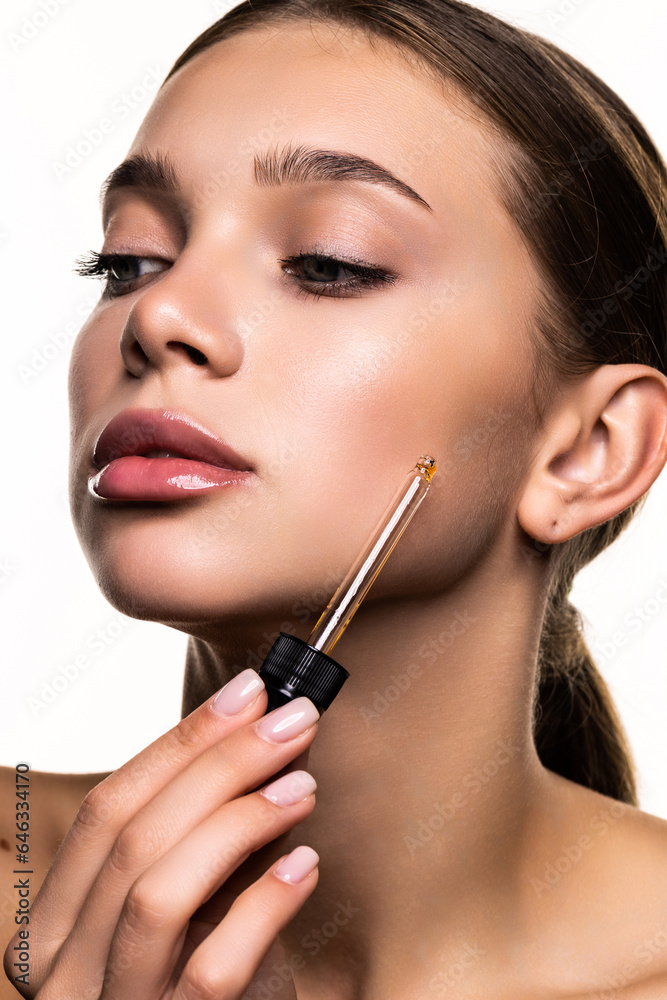 Young woman apply moisturizing facial serum, hand holding dropper with essential oil, isolated on white background. Young woman apply moisturizing facial serum, hand holding dropper with essential oil, isolated on white background.