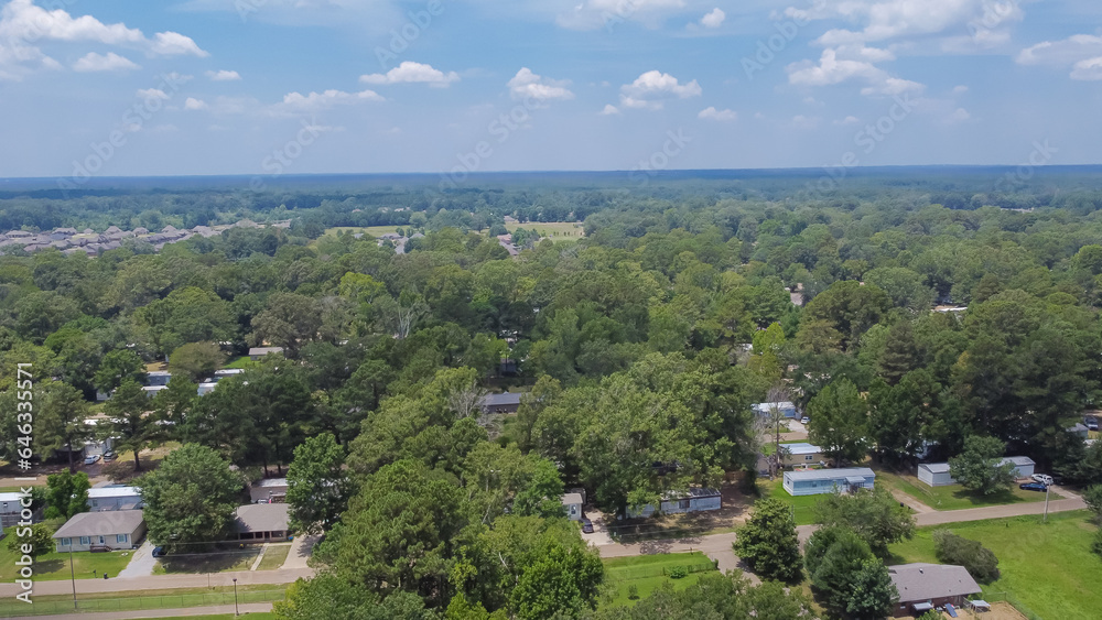 Row of manufactured, modular, and mobile homes surrounding by lush green trees in Richland, Rankin County, Mississippi suburb of Jackson, USA established neighborhood