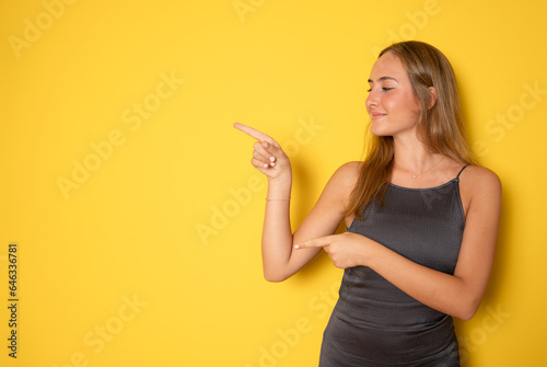 Teenager girl over isolated yellow background pointing finger to the side