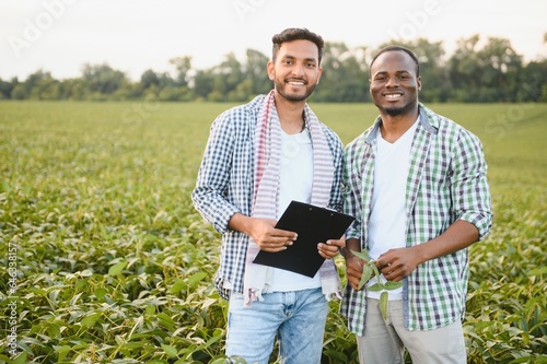 An African-American farmer and an Indian businessman in a soybean field discuss the sale of soybeans