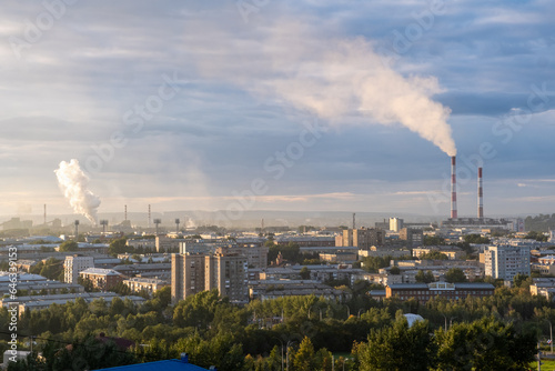 Beautiful urban area with houses and boiler room at sunset. View of the big city from above. Smoking chimneys of boiler rooms on the background of the cityscape