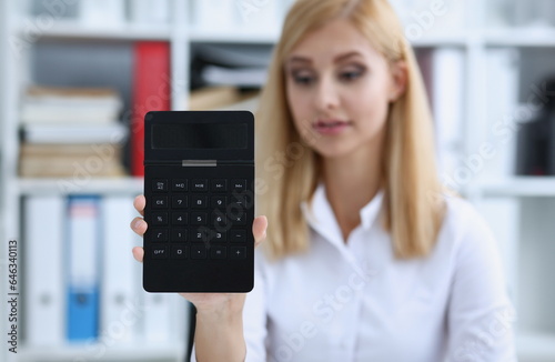 Smiling businesswoman portrait holds calculator in hand demonstrates display counting operation concept photo