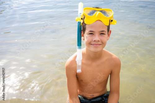 A little boy in a full face mask is snorkeling in the sea