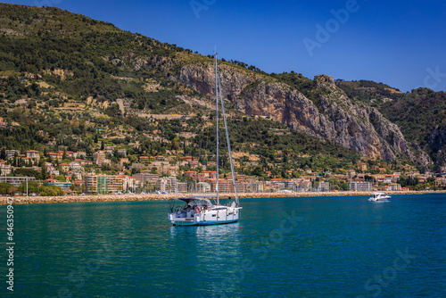 Mediterranean Sea and coastline with a beach and a boat in the water in Menton on the French Riviera, South of France on a sunny day, panoramic view