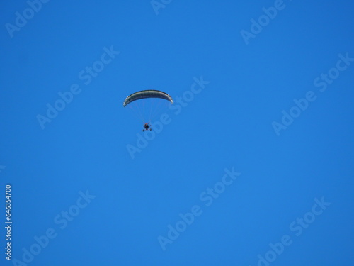 vista frontal de  parapente con vela fija color blanco y negro y motor de hélice volando bajo el cielo azul sobre las montañas del montsec aragones, huesca, españa, europa photo