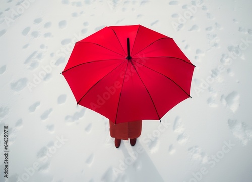 Top view, a person wearing red clothes under a red umbrella standing in the snow. Minimal season greetings concept. Generative AI
