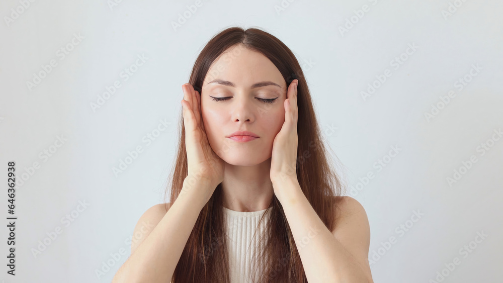 A beautiful woman gives a facial massage with her hands A beautiful woman gives a facial massage with her hands