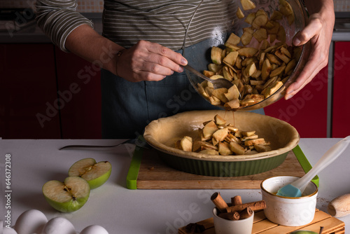 woman pouring spiced apples stuffing for the apple pie in the bakery dish with dough, lifestyle cooking process, Thanksgiving tart preparation, autumn bakery, lifestyle, Crispy weather sweets. Recipe