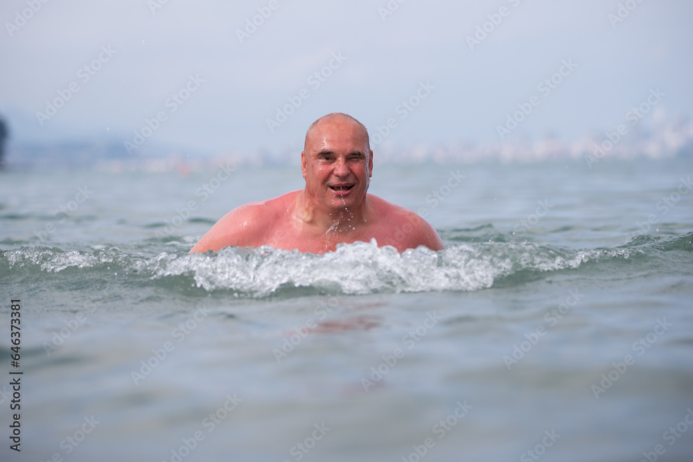 An elderly man bathes in sea water.