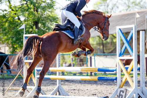 Young sportsman riding horse bounding over obstacle on showjumping competition