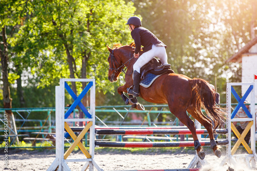 Young sportsman riding horse bounding over obstacle on showjumping competition
