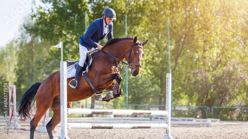 Young sportsman riding horse bounding over obstacle on showjumping competition