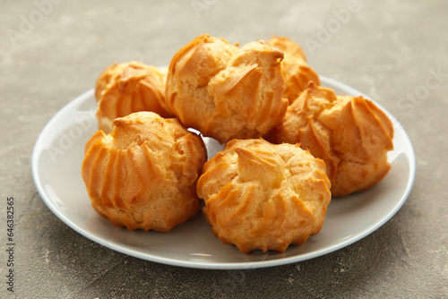Принти на полотні Homemade profiteroles with cream on plate on grey background