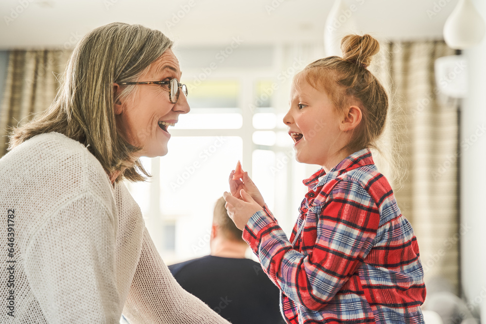 Cheerful mature woman in eyeglasses having fun with her granddaughter