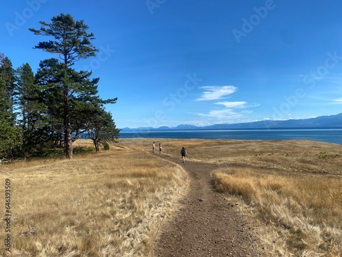 People hiking along a beautiful coastline trail on Hornby Island. Views are from a trail in Helliwell Provincial Park, on a scenic sunny summer day in the Gulf Islands, British Columbia.