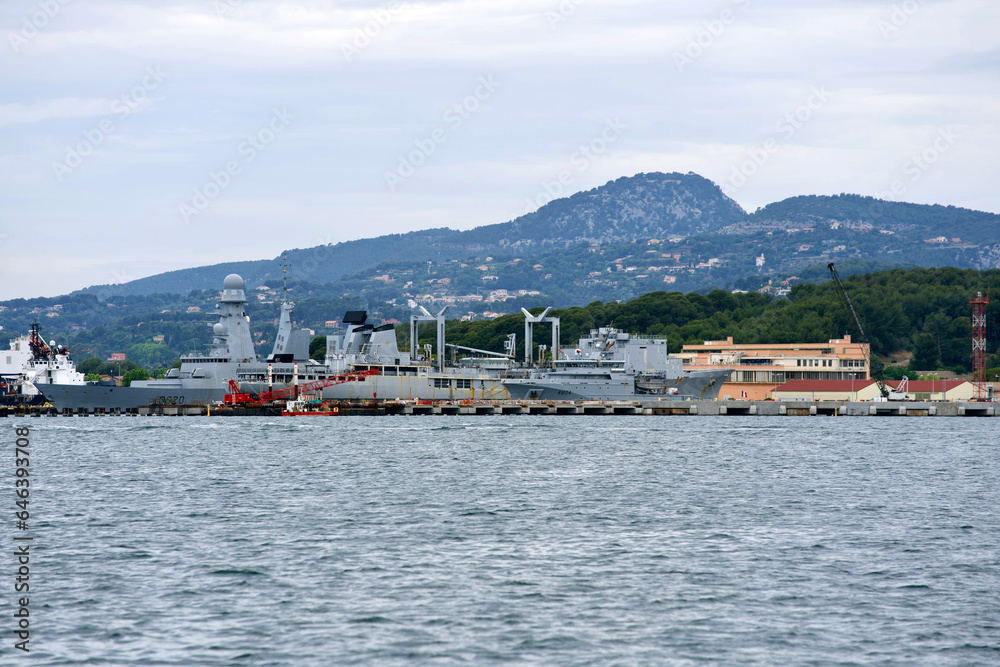 Moored warships at French Navy Naval Base at City of Toulon on a cloudy late spring day. Photo taken June 9th, 2023, Toulon, France.