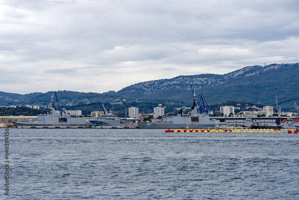 Moored warships at French Navy Naval Base at City of Toulon on a cloudy late spring day. Photo taken June 9th, 2023, Toulon, France.
