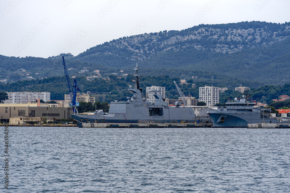 Moored warships at French Navy Naval Base at City of Toulon on a cloudy late spring day. Photo taken June 9th, 2023, Toulon, France.