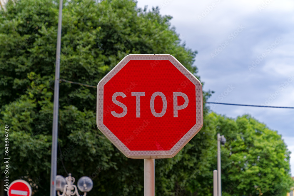 Stop sign at village Giens with trees in the background on a cloudy late spring day. Photo taken June 9th, 2023, Giens, France.
