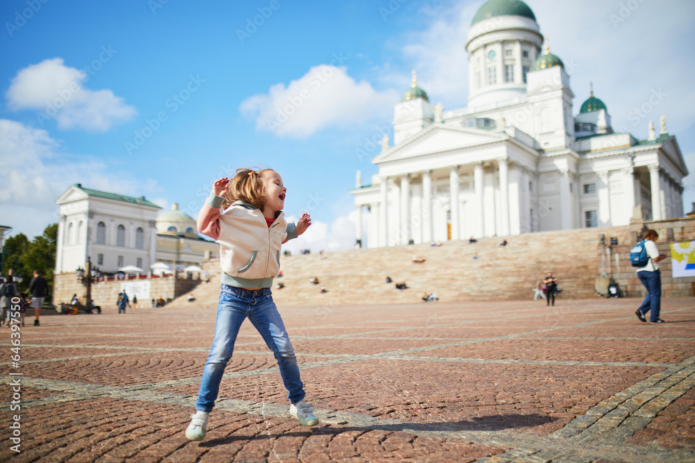 Adorable preschooler girl jumping near Helsinki Cathedral (Helsingin tuomiokirkko) in Helsinki, Finland