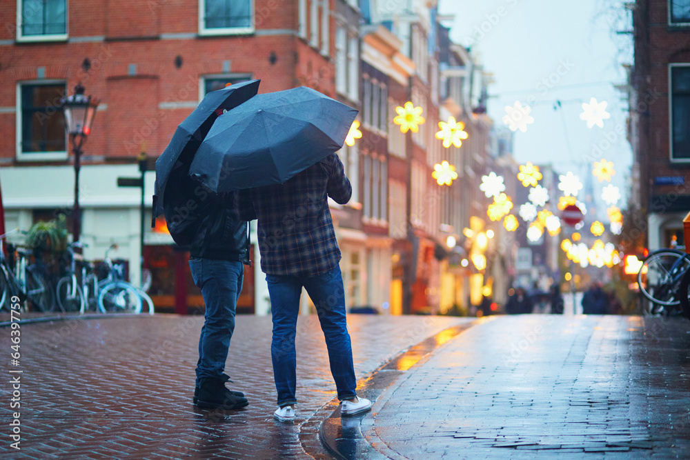 Two men with umbrellas on a street on a rainy winter day in Amsterdam, the Netherlands