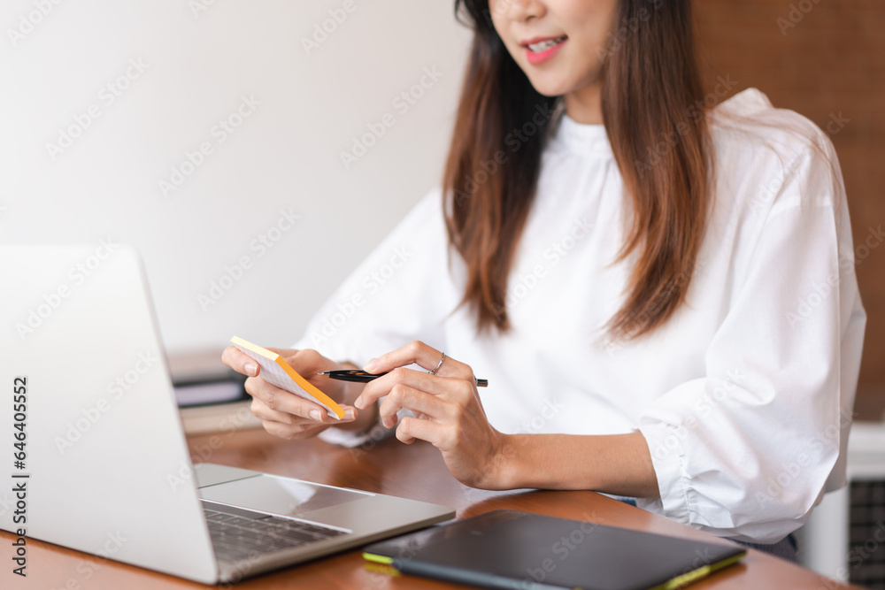 Businesswomen thinking about new startup and taking note in post it while working in outside office Businesswomen thinking about new startup and taking note in post it while working in outside office
