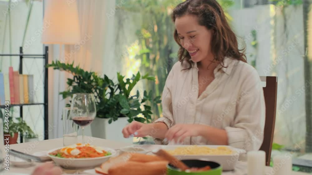 Unrecognizible man giving plate with spaghetti to his wife while sitting at festive dinner at home Unrecognizible man giving plate with spaghetti to his wife while sitting at festive dinner at home