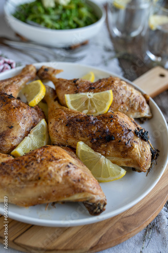 Roasted chicken legs on a dinner table with lemon