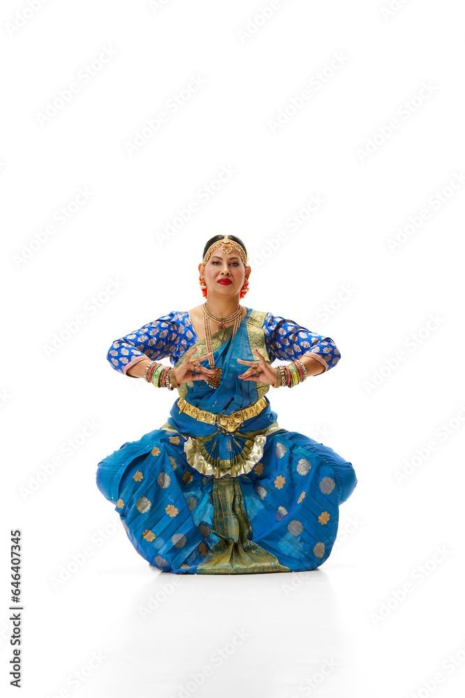 Beautiful mature indian woman in traditional dress dancing indian dance against white studio background. Concept of beauty, fashion, India, traditions, lifestyle, choreography, art. Ad