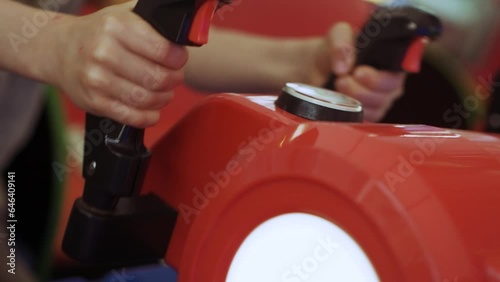 Children's hands operate a game joystick in an amusement park