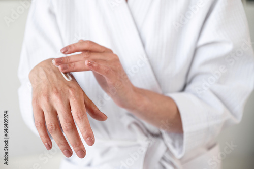 Mature woman applying moisturizer cream on hands