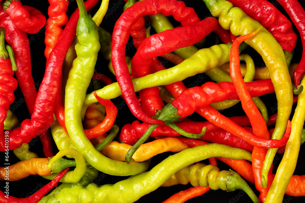 Extreme close up, top down view of many fresh, organic cayenne chili peppers in different colors on a black background. Extreme close up, top down view of many fresh, organic cayenne chili peppers in different colors on a black background.