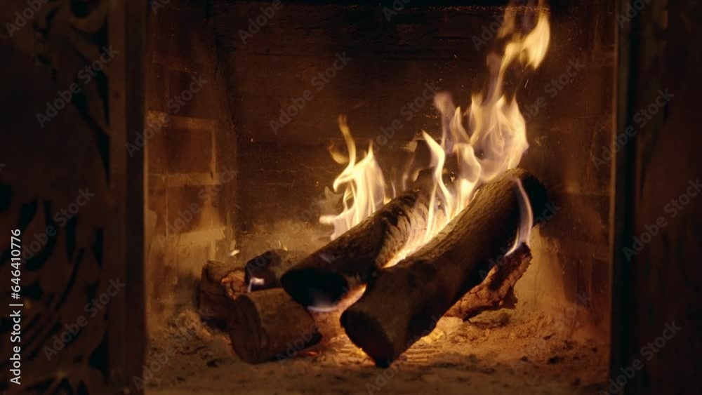 Small fireplace with burning fire wood or logs inside warming up home or room. Fire burning through the logs slowly. Cozy feeling inside during cold winter night on ski vacation or holiday