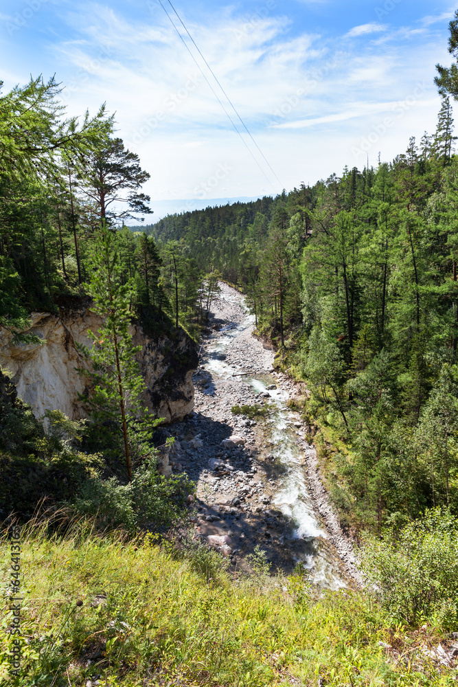 Top view of bed and gorge of mountain river Kyngarga with green forest along the rocky shores on sunny August day. Active summer holidays, hiking and traveling. Siberia. Buryatia. Arshan resort