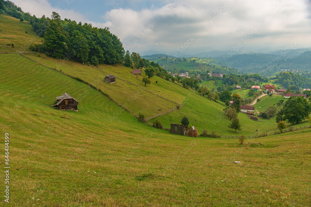 Rural idyllic landscape of the small villages in the Rucar-Bran mountain area, Brasov, Romania, scattered on the wooded hills, with the Bucegi mountains in the background, in wonderful springtime day Rural idyllic landscape of the small villages in the Rucar-Bran mountain area, Brasov, Romania, scattered on the wooded hills, with the Bucegi mountains in the background, in wonderful springtime day
