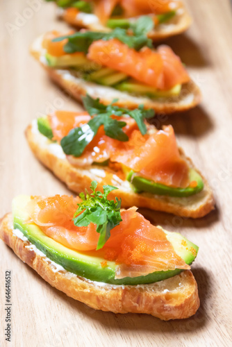 Smoked salmon with cream cheese and avocado slide on fresh croissants.