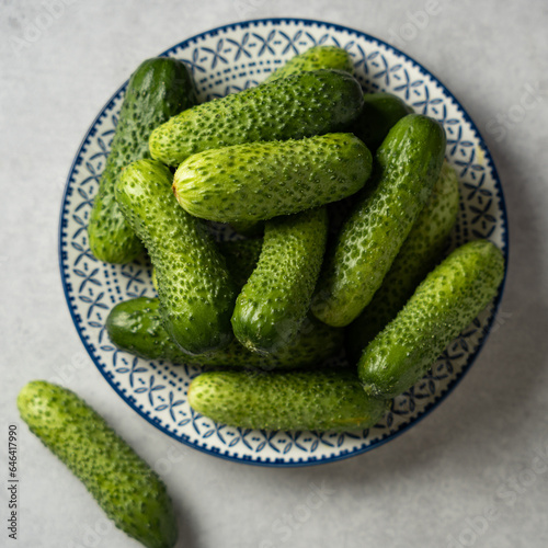 Fresh cucumbers on a plate  light gray stone background  square format