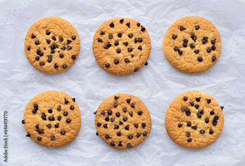 Cookies with chocolate chips on white crumpled paper. Close-up, top view, flat layout