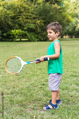 smiling cute child playing with an old tennis racket in a public park