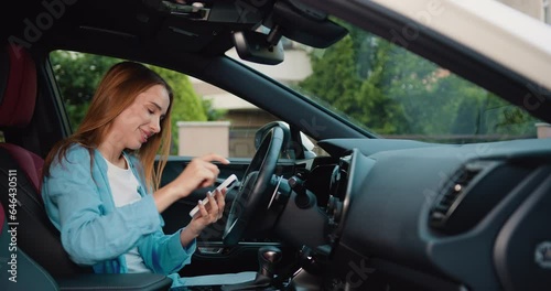 Wallpaper Mural Cheerful blonde girl with freckles sitting in modern car and using mobile phone for surfing internet social media e-mail. Woman using touch screen in car setting up the navigation gps application on Torontodigital.ca