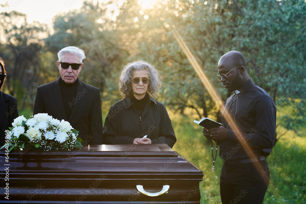 Young pastor reading verses from Holy Bible while standing in front of