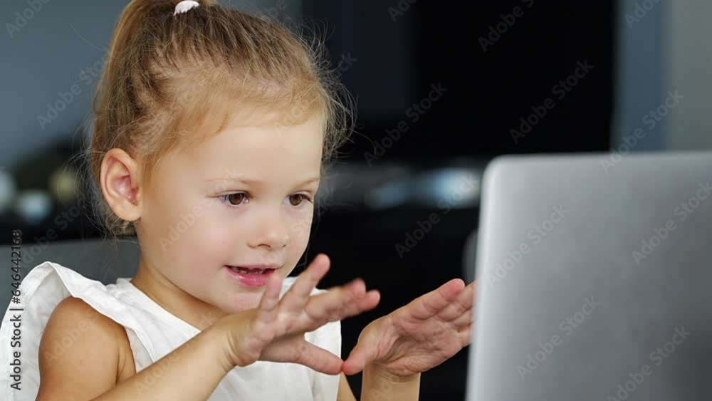 Little girl does finger gymnastics online on the laptop home. Distance learning concept. Little girl does finger gymnastics online on the laptop home. Distance learning concept.