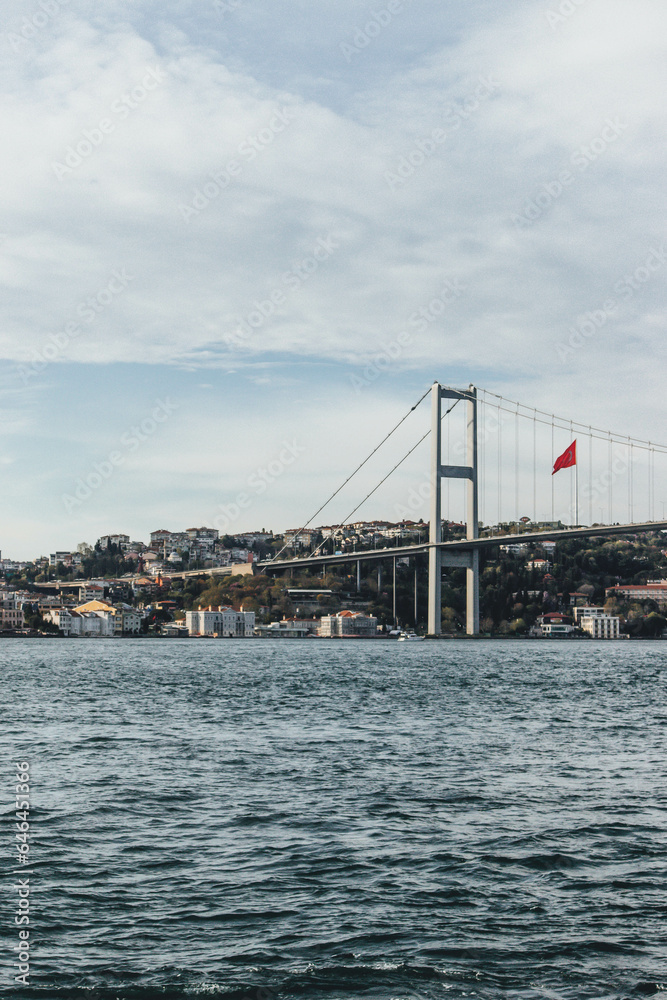 View of bosphorus strait water at sunset with beautiful light and bridge with skyline and huge flag