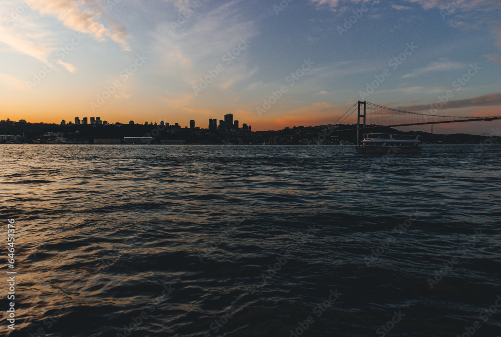 View of bosphorus strait water at sunset with low light and skyline with bridge at horizon